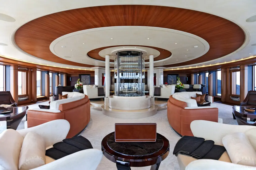 Large round saloon on Serene with a glass column in the centre and curved sofas under a wooden ceiling