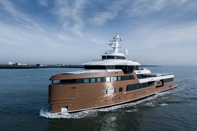 La Datcha underway in calm water, side view of the bronze hull and white upper decks