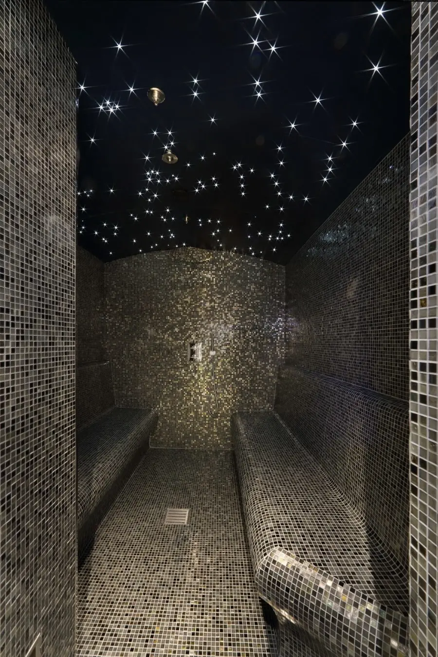 Hammam lined with dark mosaic tiles and a star-lit ceiling