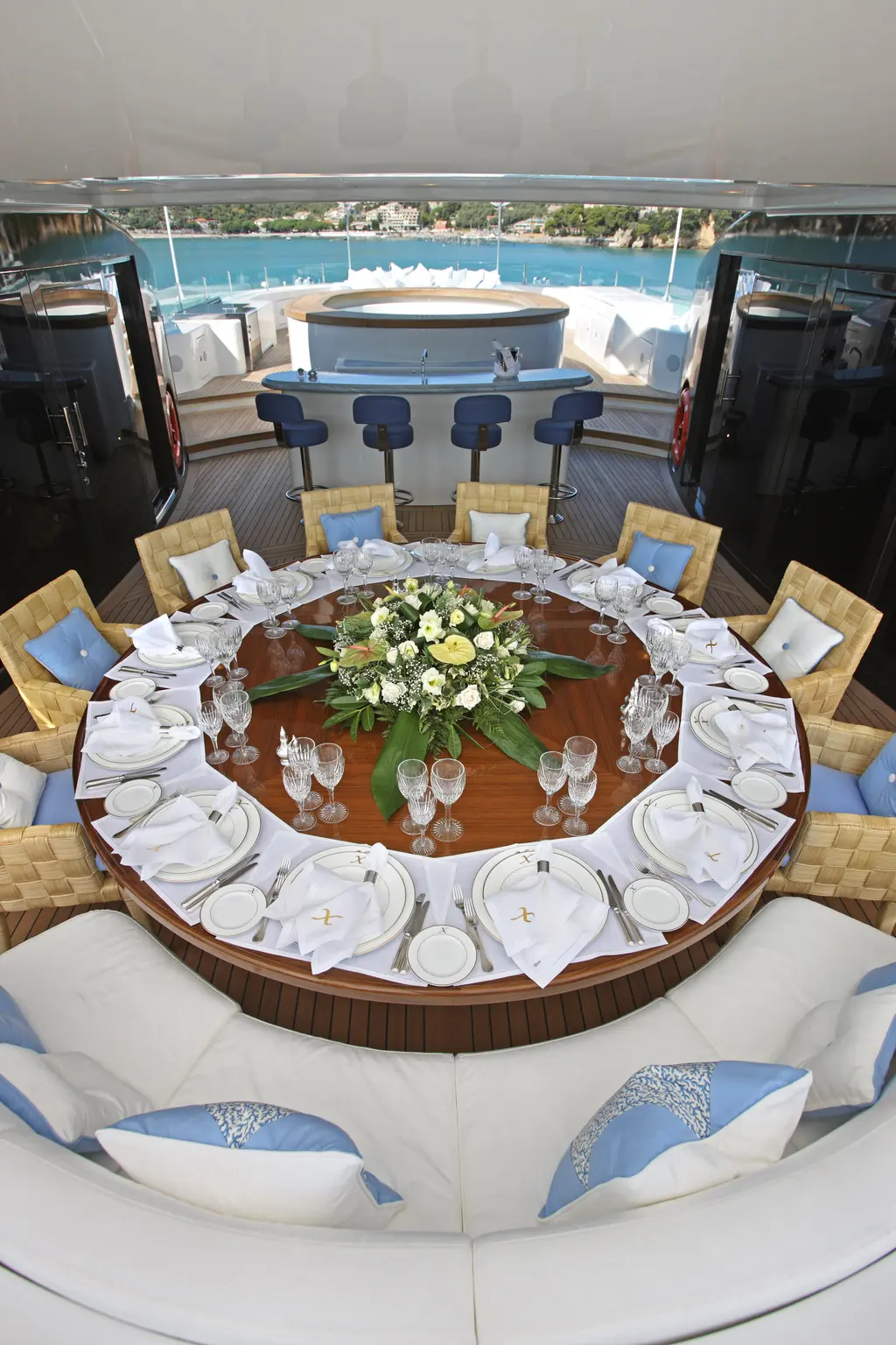 Round outdoor dining table laid for a dinner, bar stools behind
