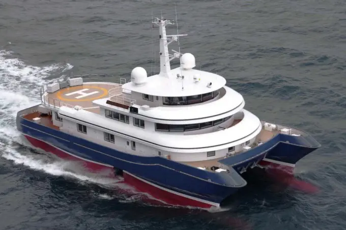 Silver Cloud under way seen from above at three-quarters, blue twin hull, white superstructure and helipad aft