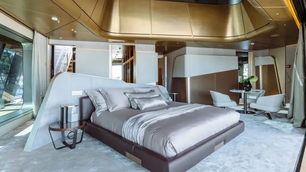 Large cabin with a double bed, a sculpted headboard, a gold-toned ceiling and a small seating area
