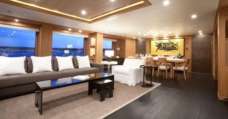 Main salon with pale sofas, wood-panelled walls and a dining area beyond