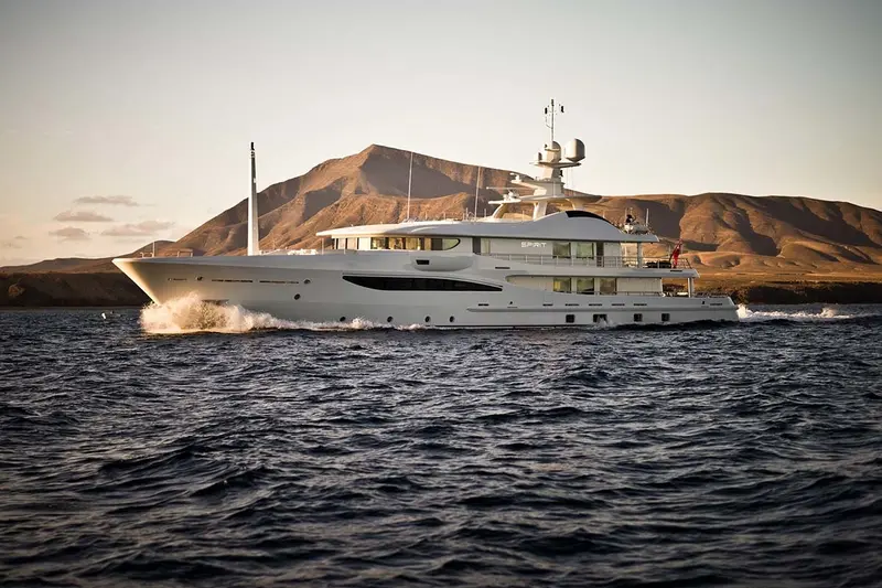 Spirit underway at dusk in front of a bare brown hillside