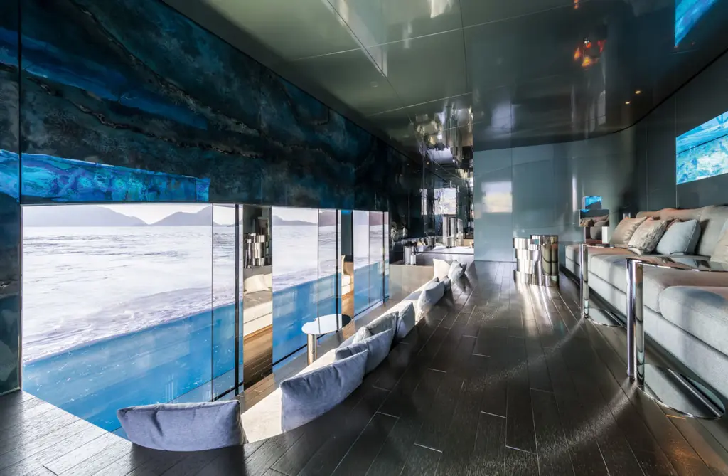 A long sofa beside a glass wall in the hull, the sea surface visible across the middle of the glass