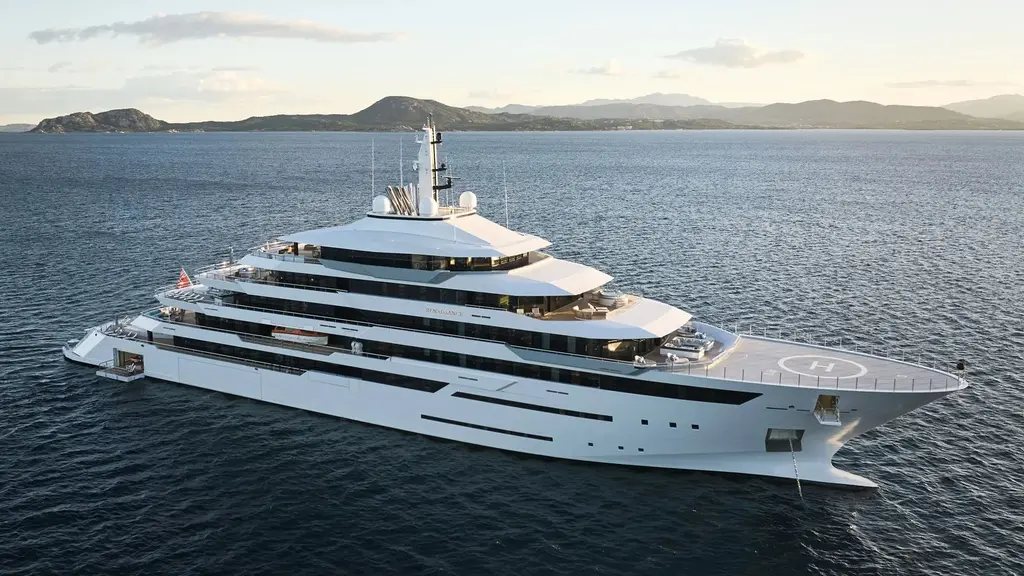 Renaissance at anchor, aerial view from the stern quarter, white hull and a helipad on the bow