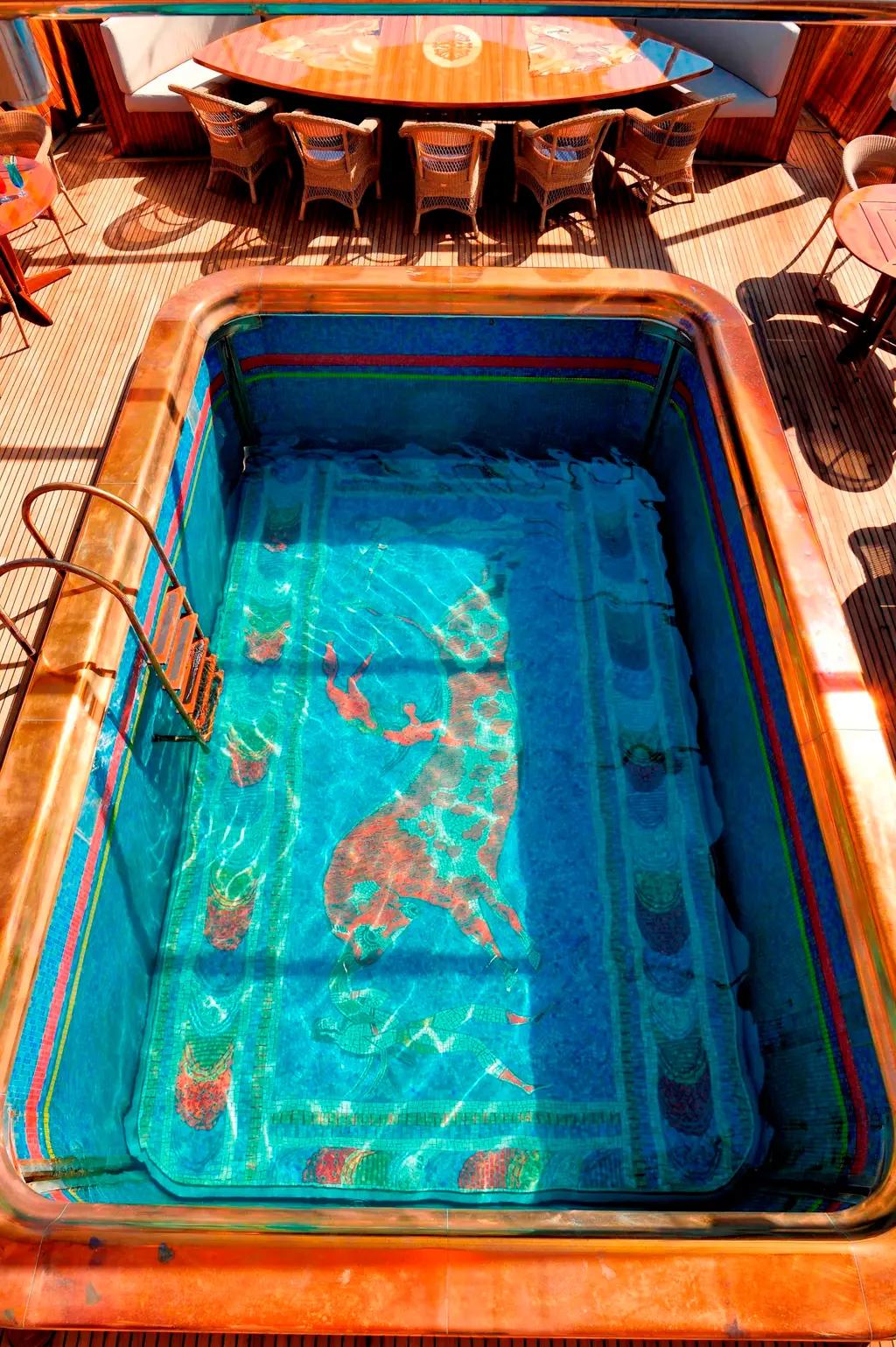 Saltwater pool on the aft deck with a mosaic of a bull on the floor, dining table beyond