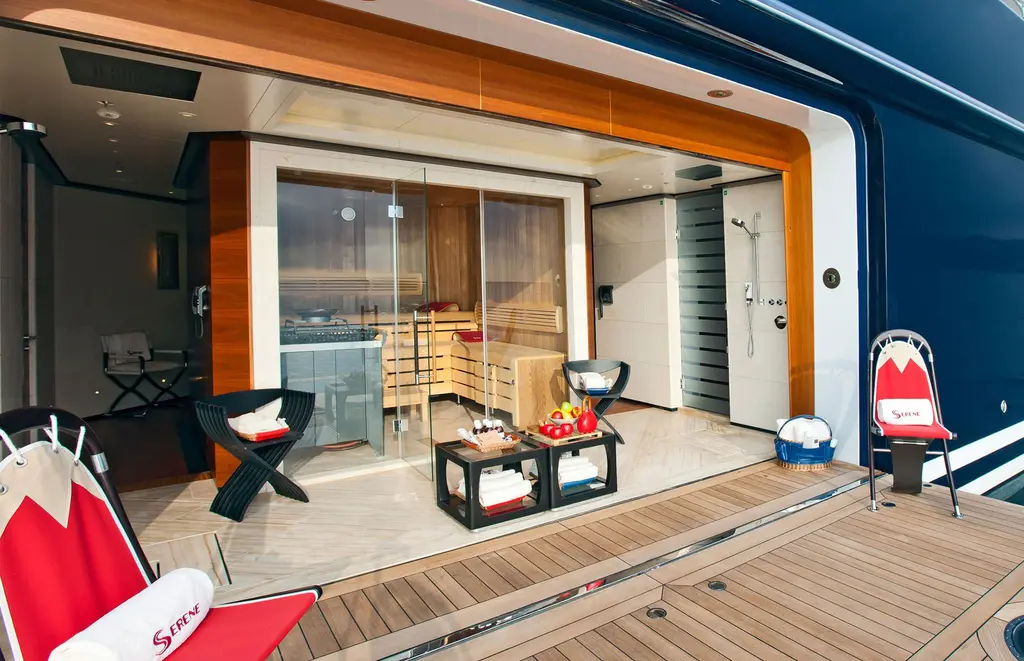 Glass-fronted sauna opening onto a teak platform at the hull side of Serene