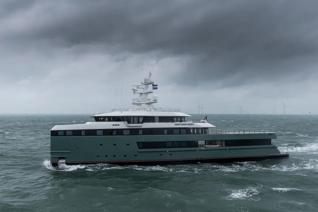 Anawa's full length from the port side in rough water under low cloud, with the long open aft deck behind the superstructure