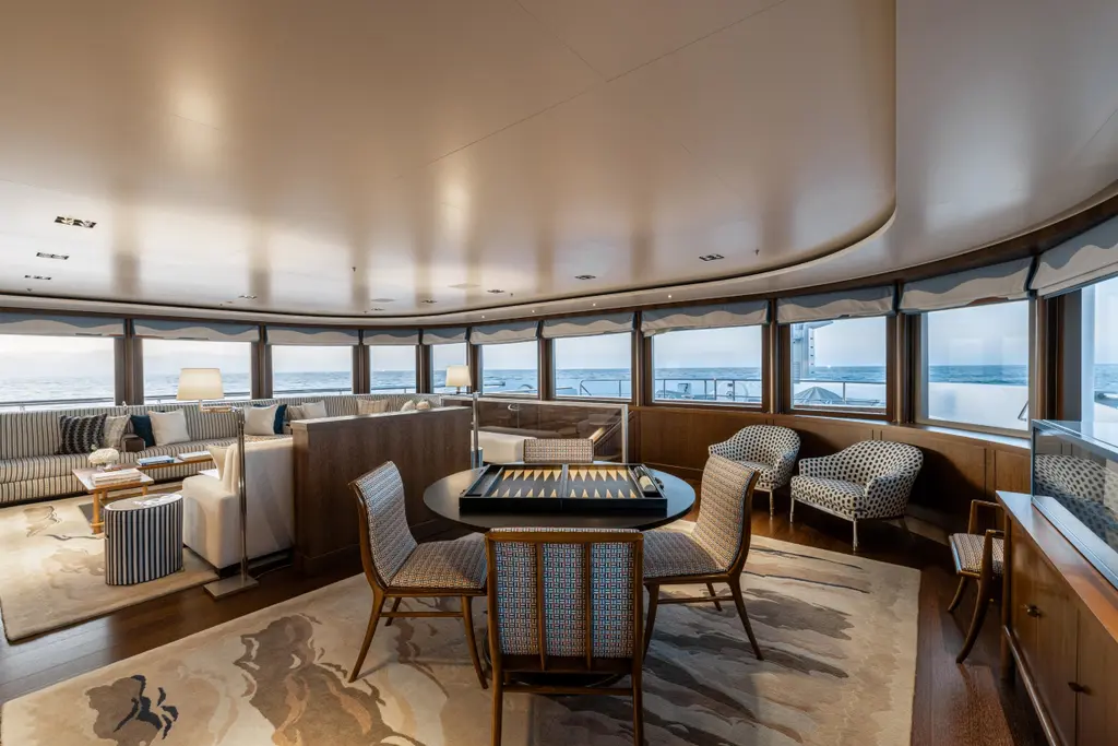 Observation lounge with a curved row of windows across the front of the deck, a games table with a backgammon board and armchairs