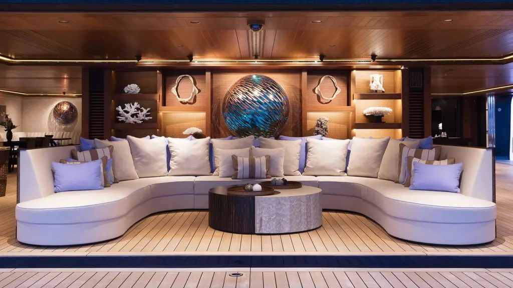 Curved white sofa in the beach club below a round blue glass sculpture