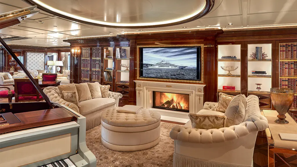 Main saloon with a painted grand piano, fireplace and leather-book walls