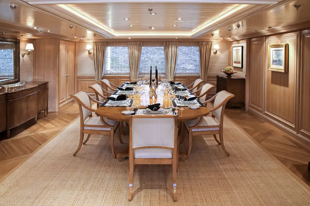 Dining room with an oval wooden table, upholstered chairs and wood-panelled walls