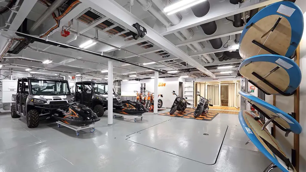 Garage with all-terrain vehicles, jet skis, motorbikes and paddleboards on racks