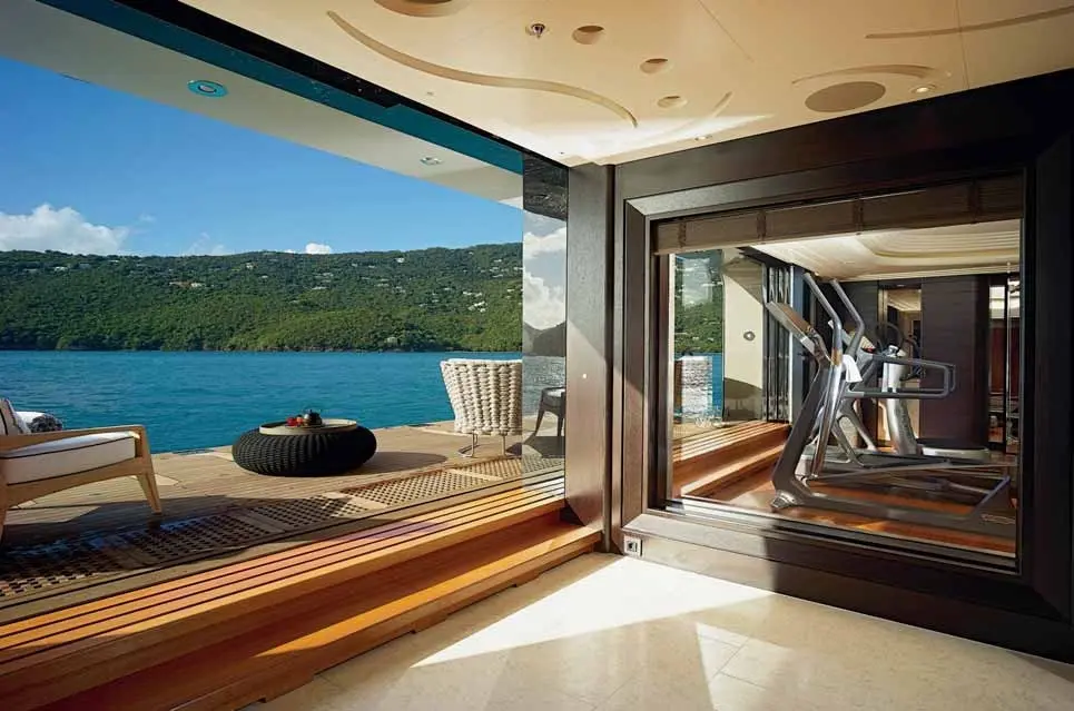 Gym with its side opened onto a fold-down sea terrace above the water