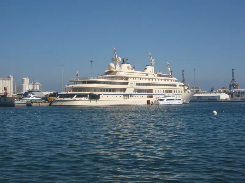 Al Said moored in a commercial port under a clear sky, a tender alongside