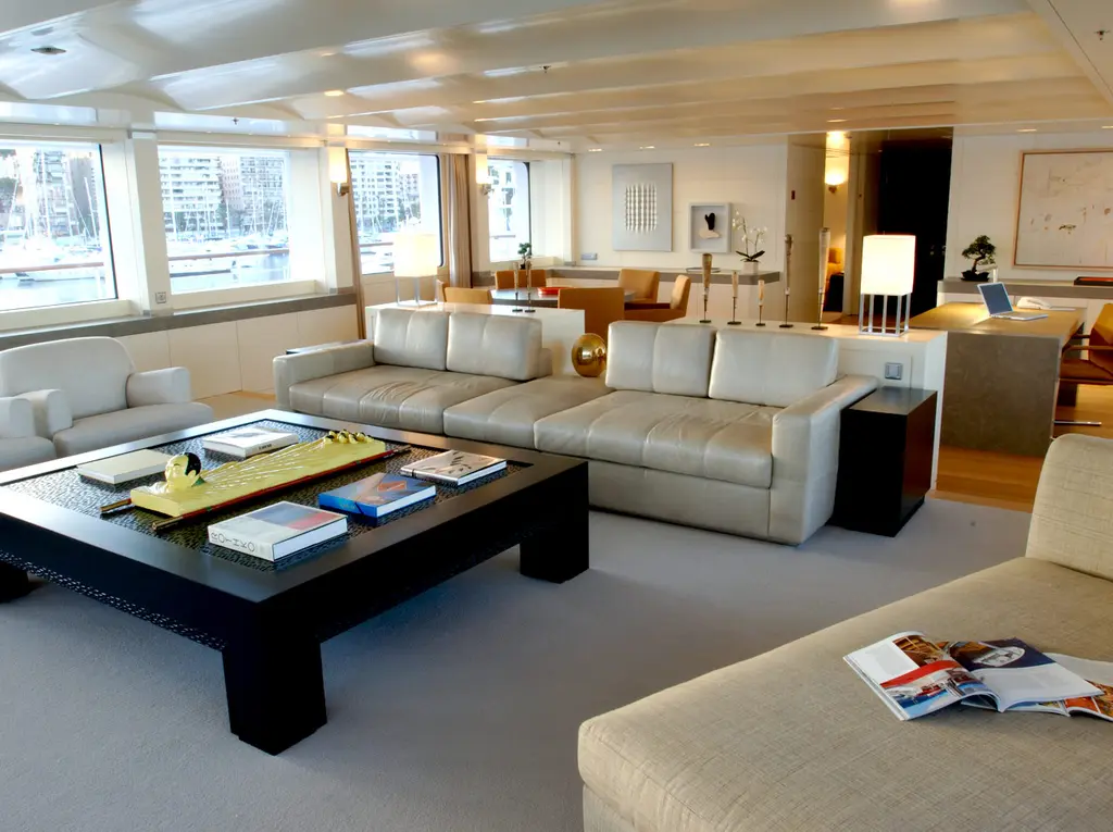A salon with cream sofas, a low dark wooden table and large windows