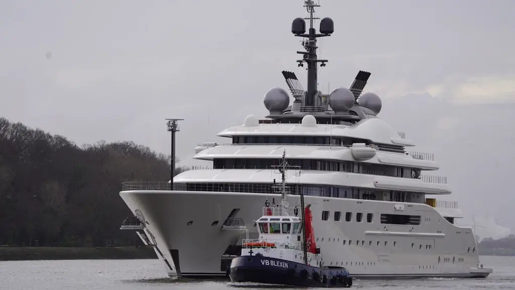 Blue's bow and stacked white decks with a harbour tug in front of the bow, radar domes on the mast