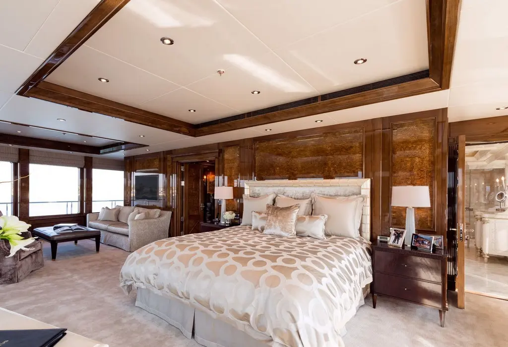 Master suite with a large bed, wood-panelled walls and a sitting area