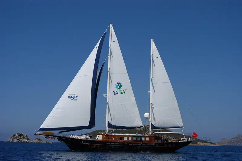Sea Dream under full sail, dark hull with varnished wood superstructure, Turkish flag at the stern