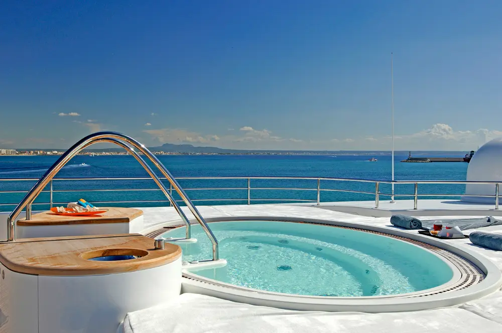 A circular whirlpool with a steel handrail on an upper deck overlooking the sea