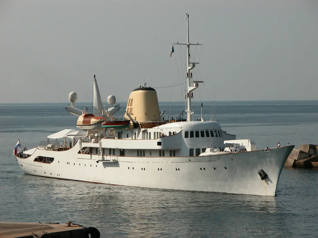 Christina O entering a harbour past a breakwater, bow and yellow funnel in view