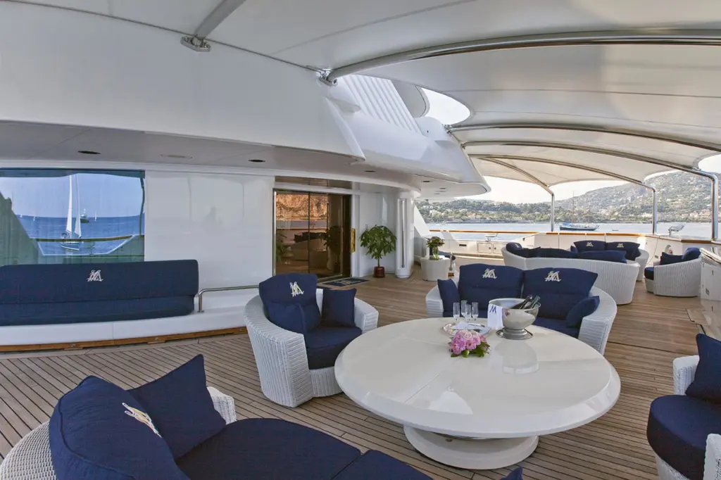 Shaded deck lounge with navy-blue sofas and a round white table