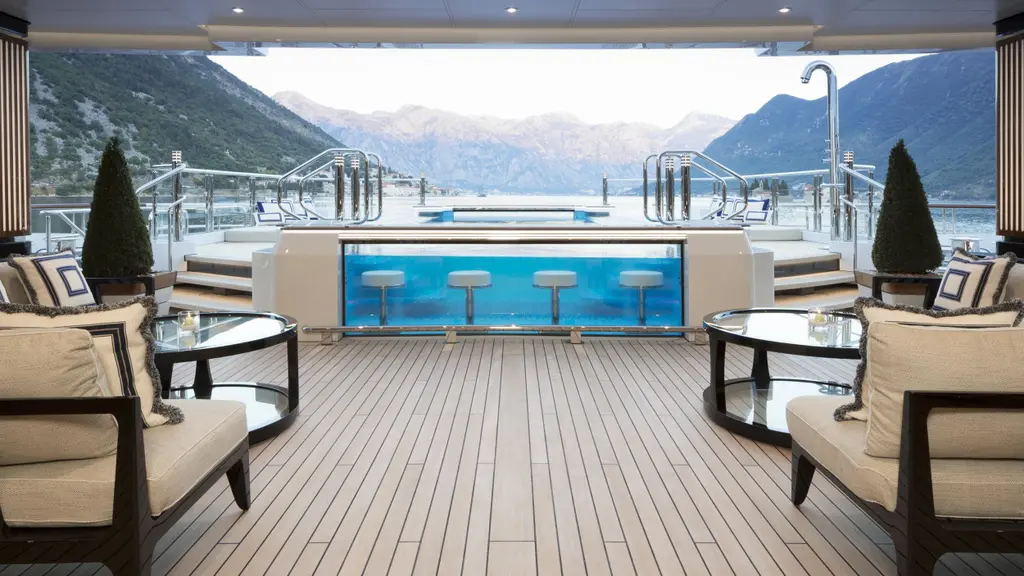 Aft deck lounge facing the glass-sided pool with submerged bar stools