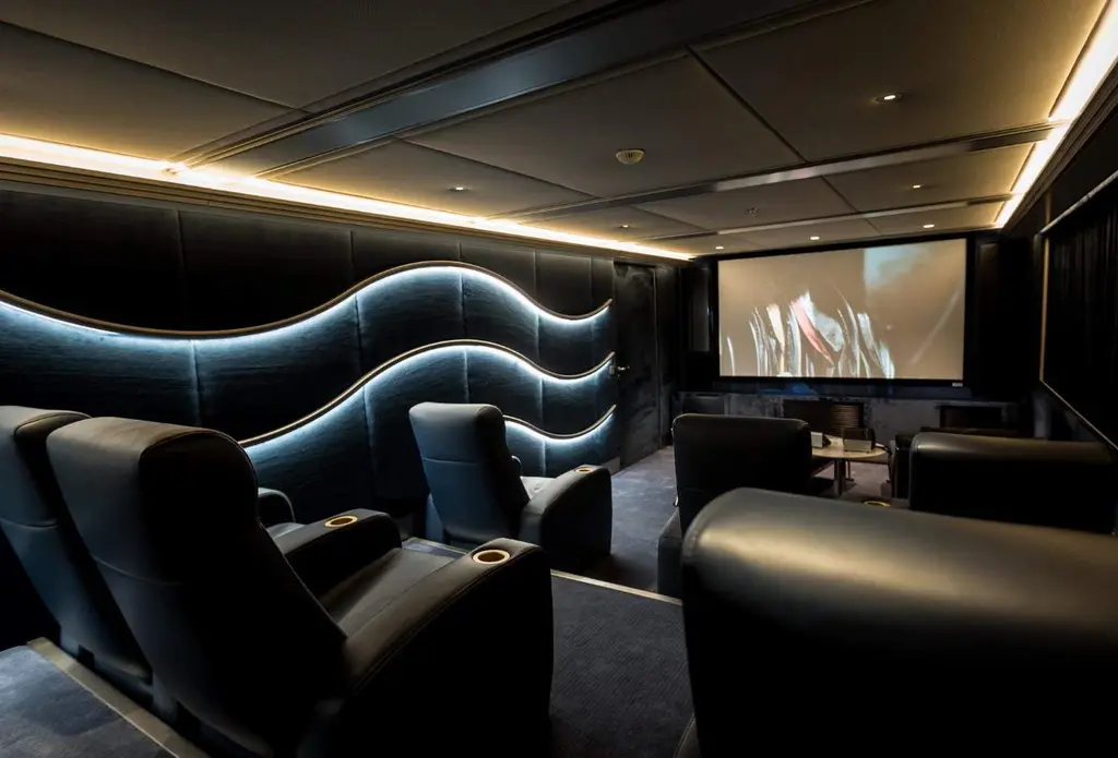 Dark cinema room with leather recliners, a wave-shaped light strip and a screen