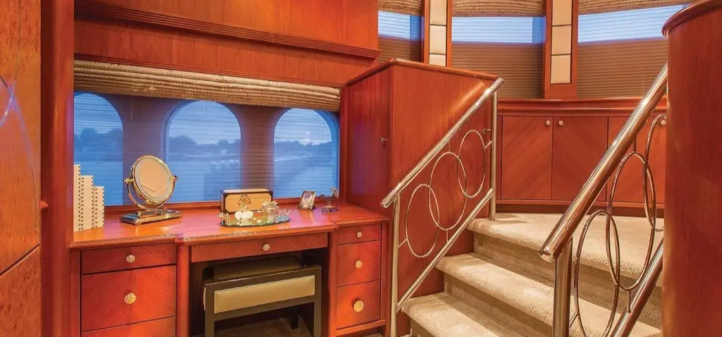 Staircase with a curved metal balustrade beside a vanity desk and arched windows