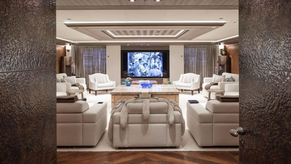 Salon with cream armchairs and sofas facing a large screen