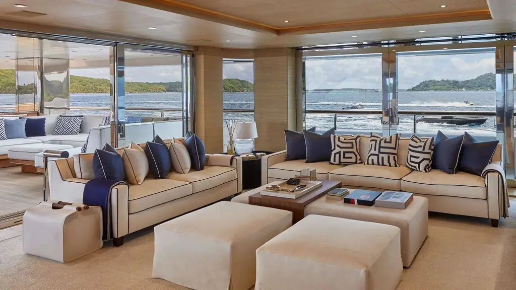 Saloon with cream sofas, navy and white cushions and floor-to-ceiling windows looking out to sea