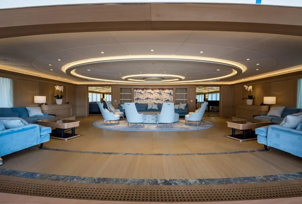 Saloon with pale blue sofas around a round rug under a recessed oval ceiling