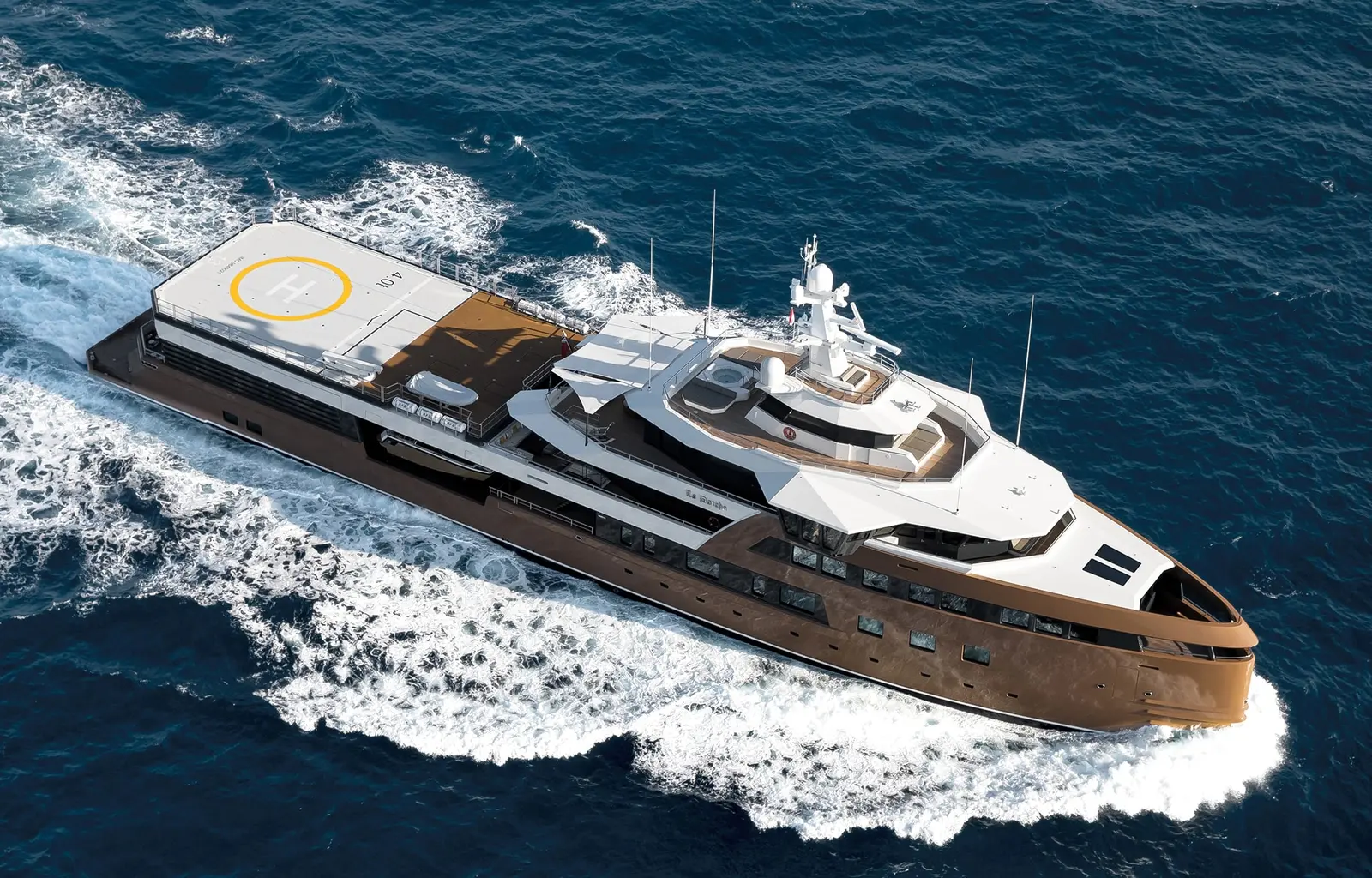 Aerial view of La Datcha at speed with white wake, showing the helideck aft, the upper decks and the high bow