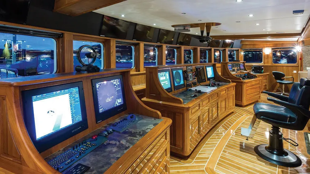 Legend's wheelhouse with free-standing wooden consoles carrying navigation screens and a high helm chair