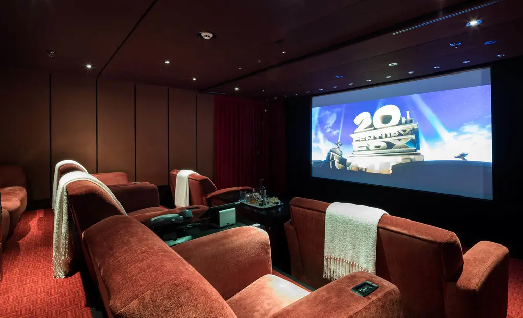 Cinema with red reclining armchairs facing a large screen