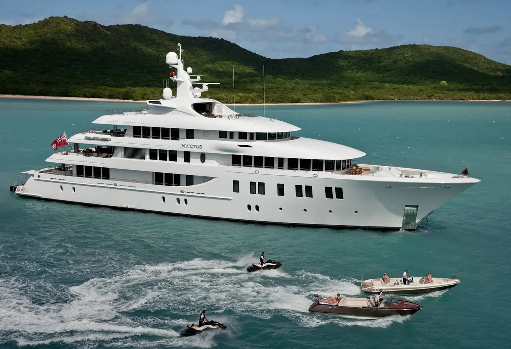 Invictus at anchor in a turquoise bay with a tender and jet skis alongside
