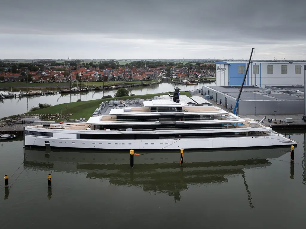 Ulysses in full profile alongside the Feadship yard, white hull with a dark window band and stacked white decks