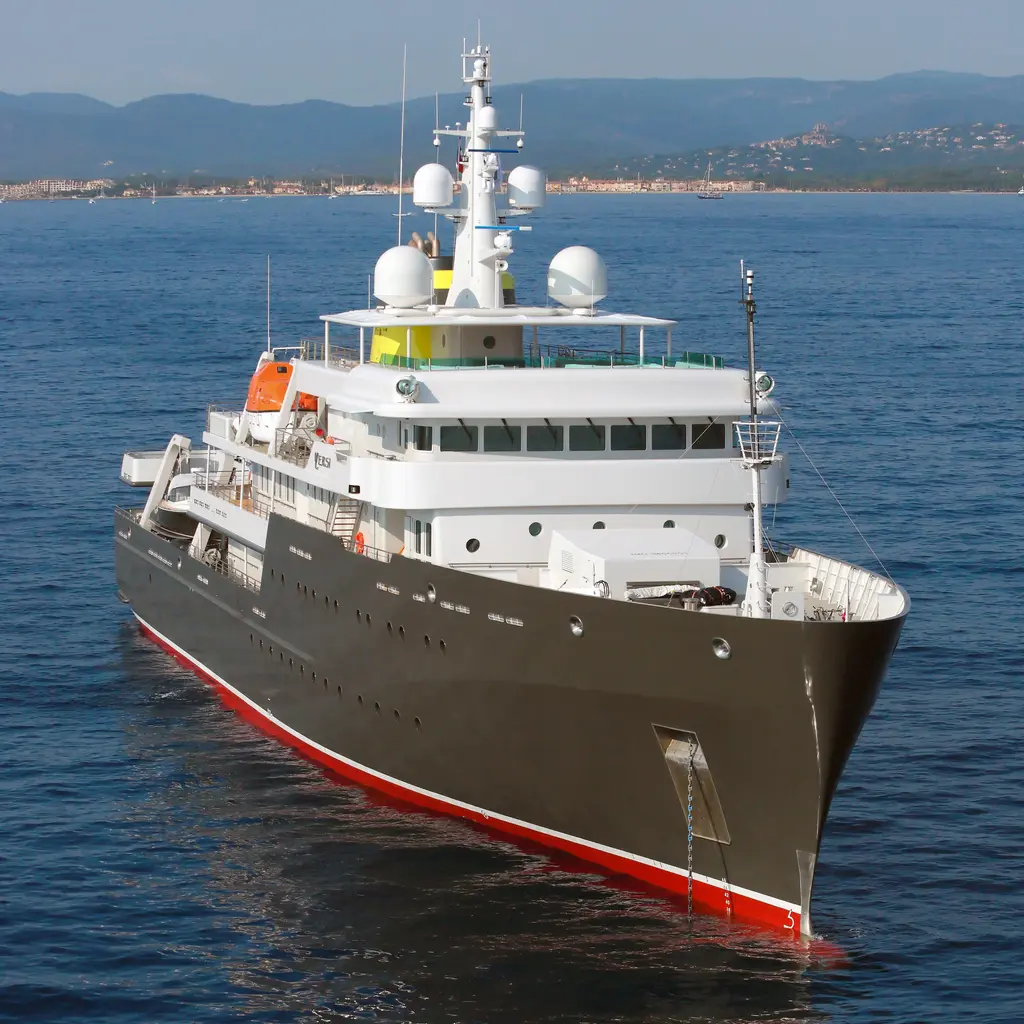 Aerial view of Yersin from ahead on a calm blue sea, showing the high bow, the radar domes on the mast and the red boot-top