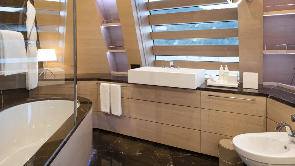 A bathroom with a bathtub, a rectangular basin on a pale wood vanity and strip windows above