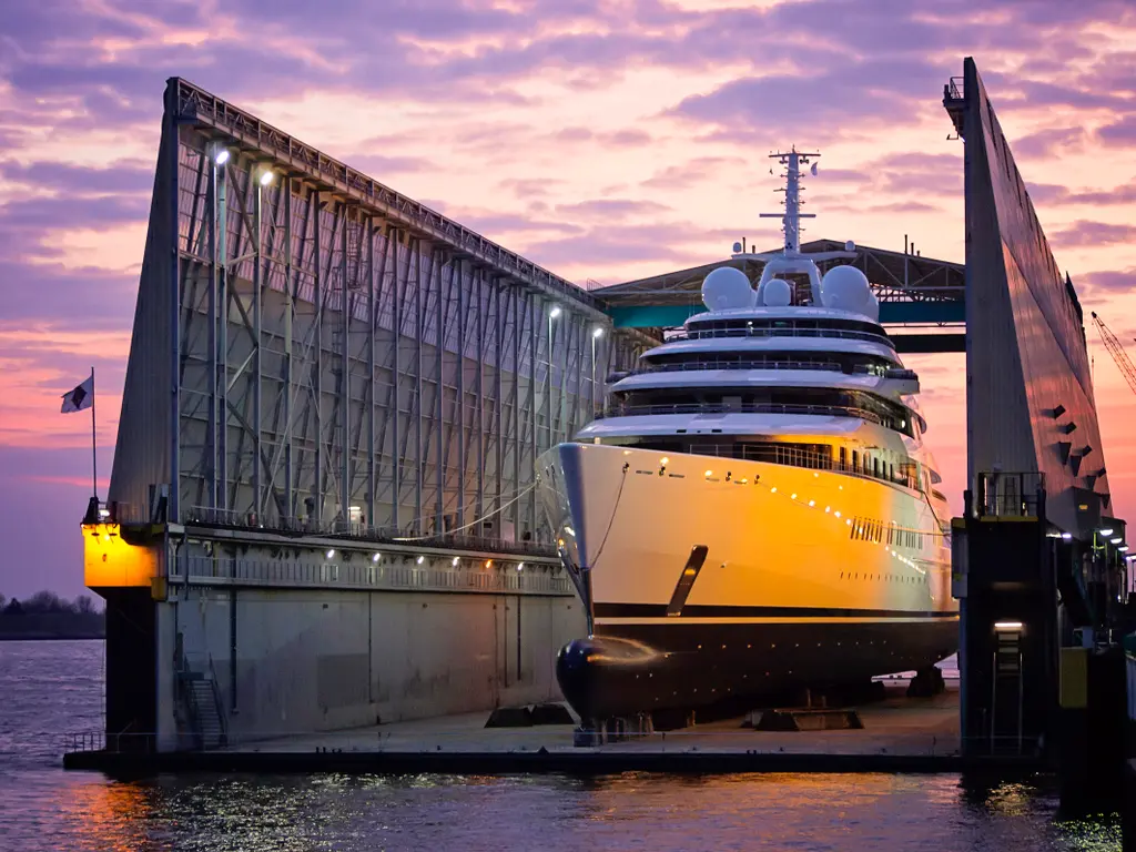 Azzam's bow inside a covered floating dock at dusk, lit in orange light