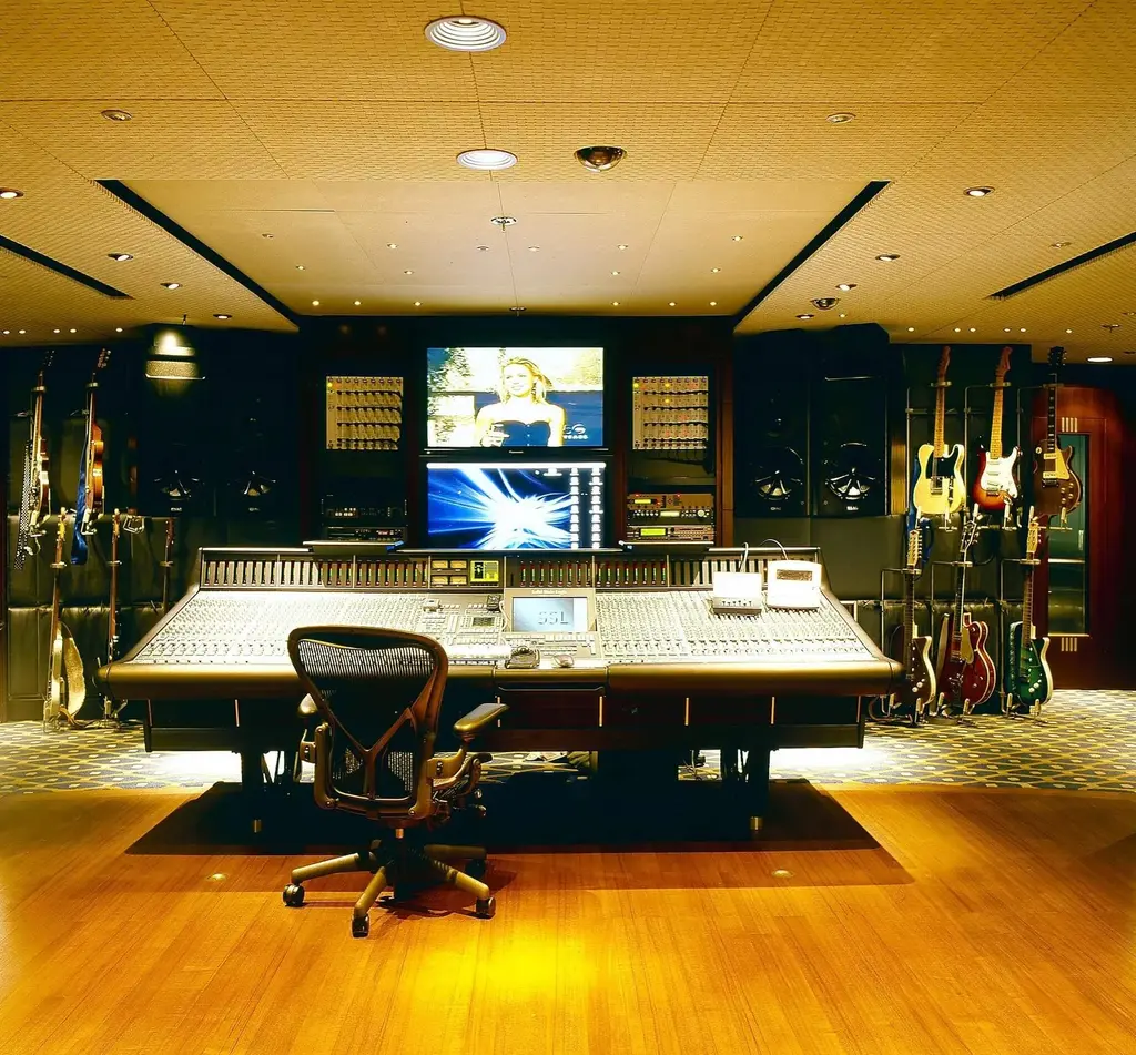 Recording studio with a mixing desk and guitars on the walls