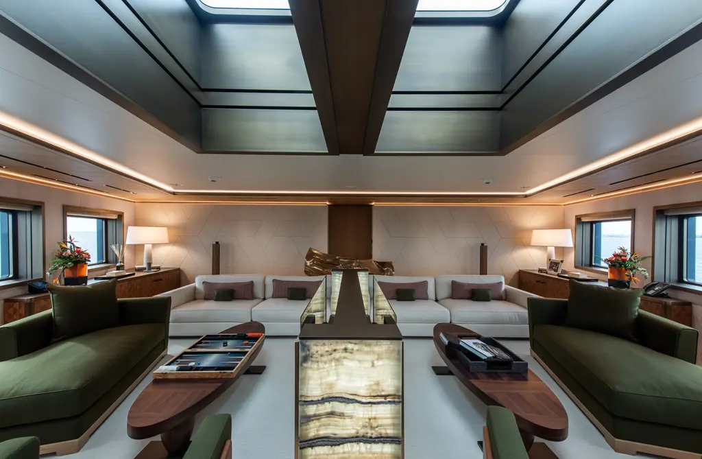Saloon with green sofas around a long low table lit from inside, under a ceiling with skylights