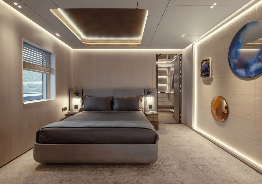 A double cabin with a low grey bed, light grey panelling, lit edges in the ceiling and round blue and amber artworks on the wall