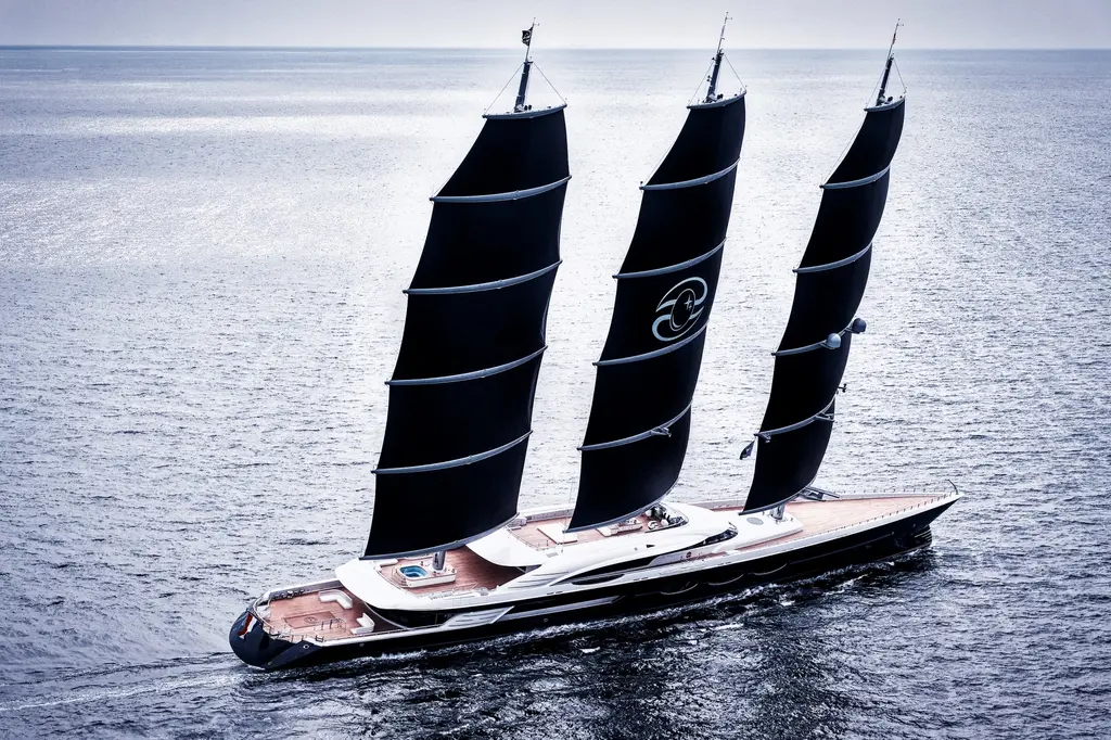 Aerial view of Black Pearl under full sail, showing the teak decks, the pool aft and the three black DynaRig sails with the yacht's emblem