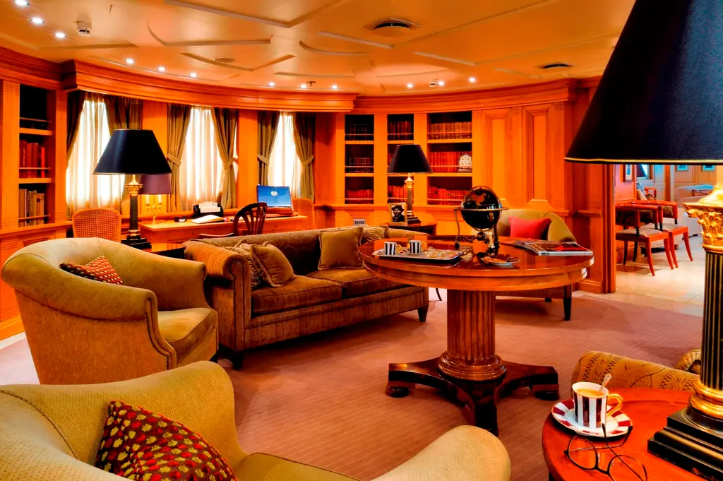 Panelled lounge lined with bookshelves, armchairs and a globe