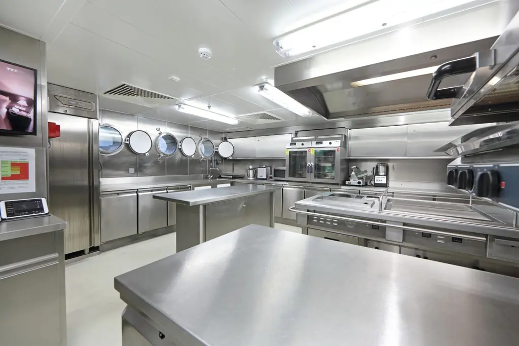 Large stainless-steel galley with work tables, ovens and an extractor hood