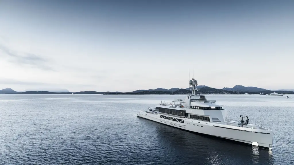 Bold at anchor in a calm bay, seen from the starboard bow, with a low mountainous coast behind