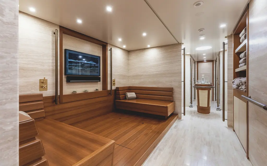 A spa room in travertine and teak with a stepped wooden bench, a screen on the wall and a corridor leading to treatment rooms