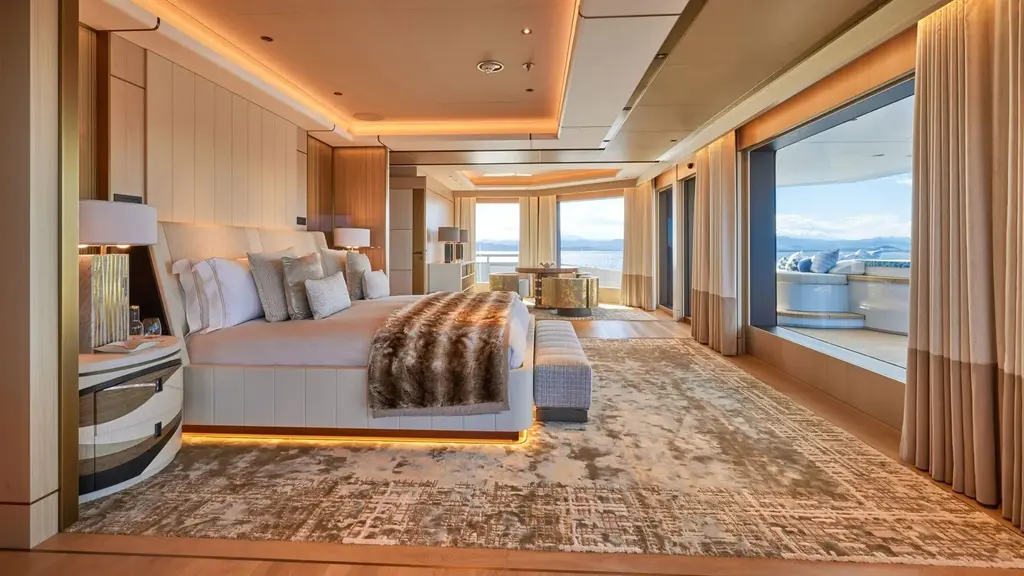 Large stateroom with a double bed, fur throw and glass doors to a private deck